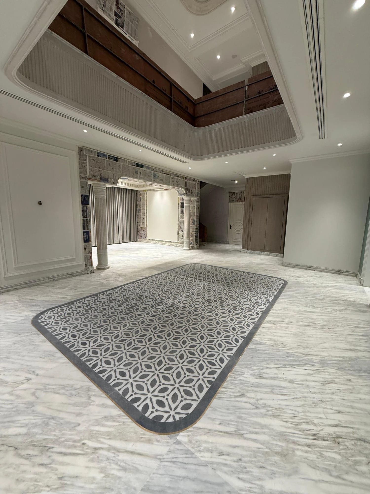 Geometric marble and grey stone inlaid floor carpet in a double-height hall