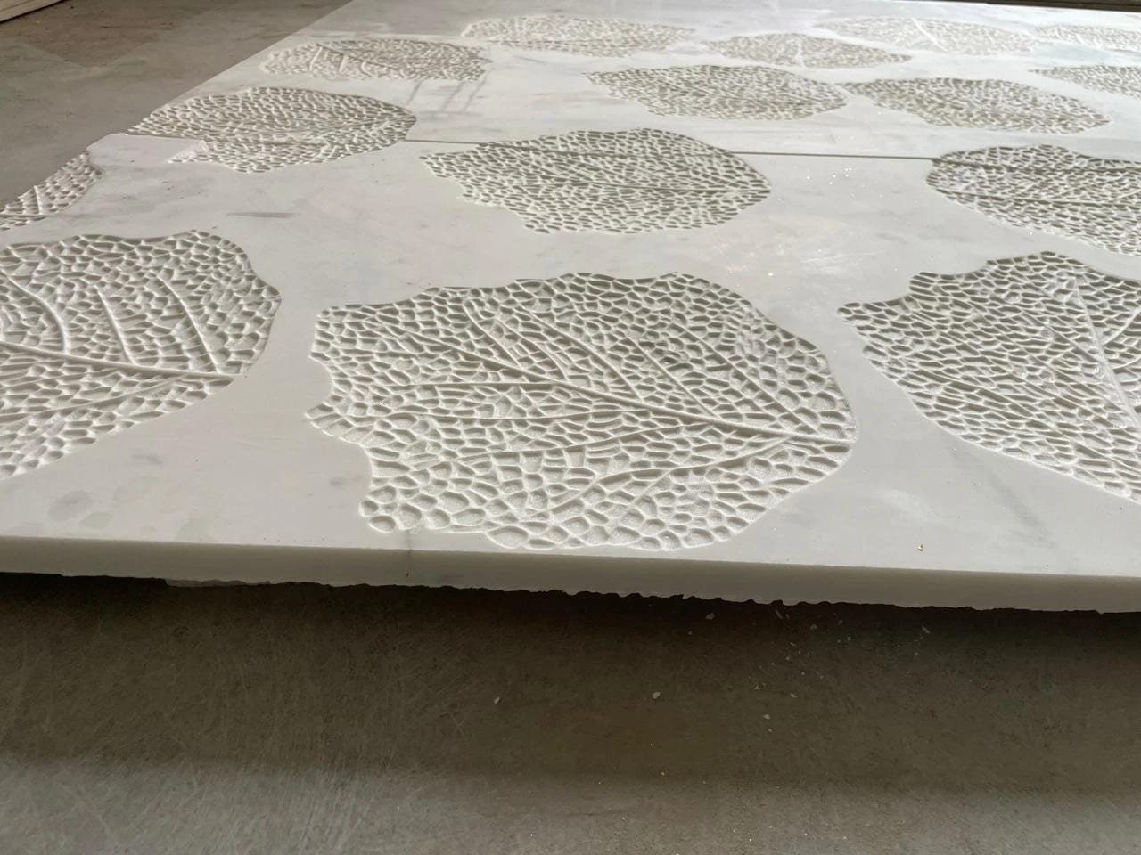 Close detail of hand-finished white marble leaf relief in the Jaipur workshop