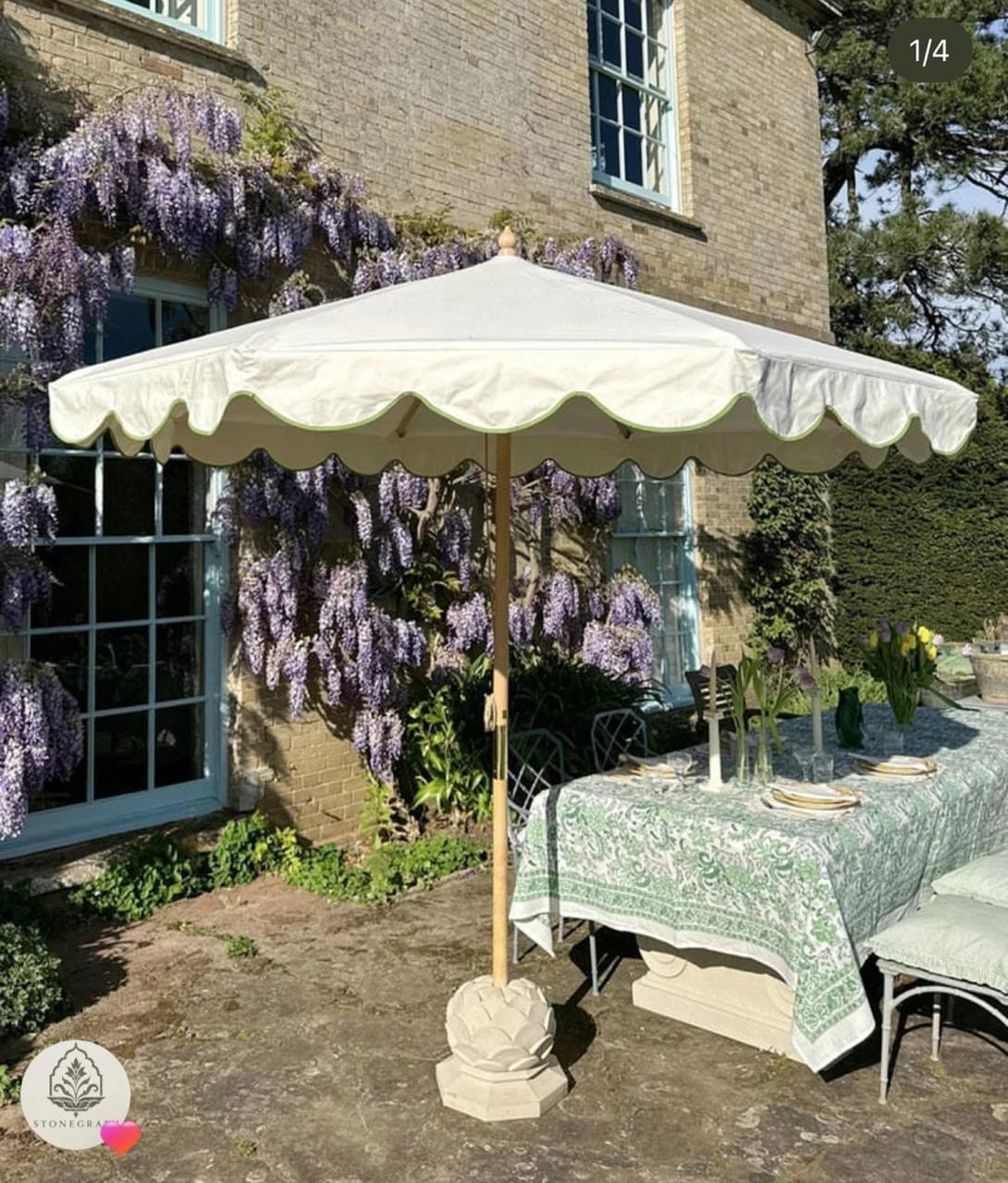 Octagonal carved sandstone lotus parasol base under a flowering wisteria
